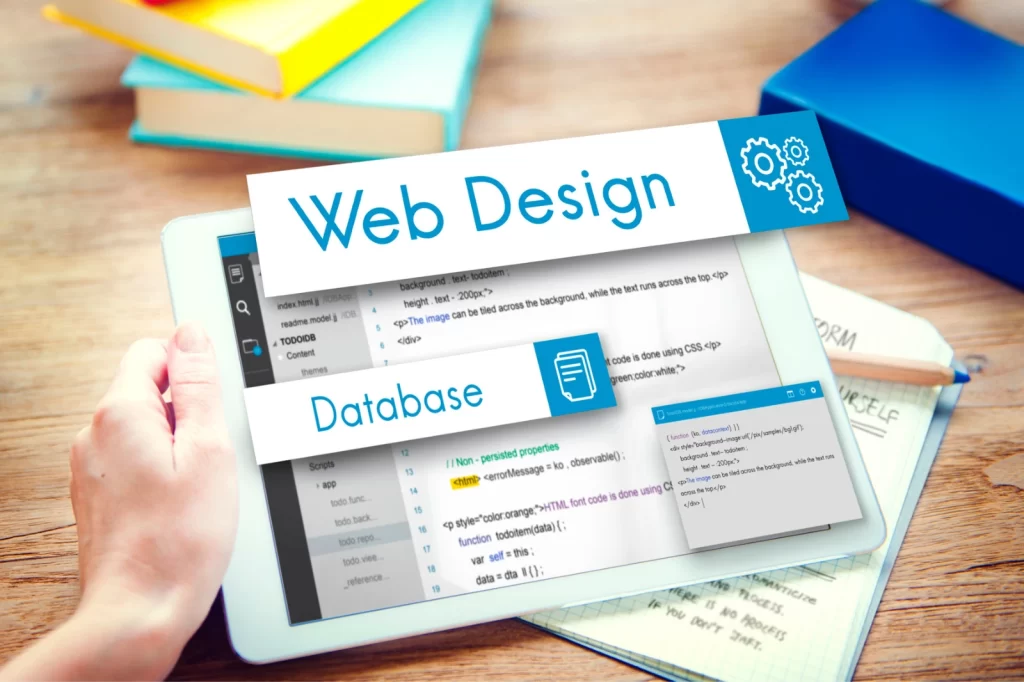 A tablet displaying code snippets for web design and database development, surrounded by stationery items on a wooden desk.