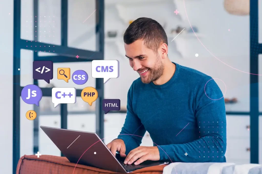 A smiling developer working on a laptop surrounded by colorful speech bubbles displaying coding languages and web development tools like JavaScript, PHP, HTML, and CMS.